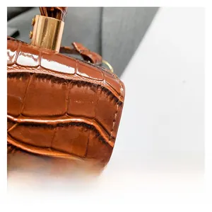 Detail of brown crocodile pattern leather with golden metal handle fasteners on handbag