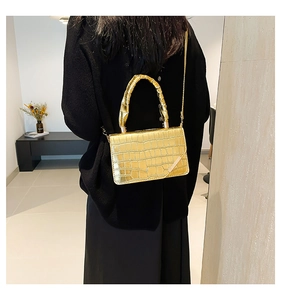 Detail of metallic gold crossbody bag with luxury crocodile texture and handle