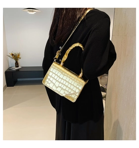 Close-up of golden croc-embossed handbag featuring a unique bamboo handle and metallic finish
