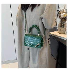Detail of green crocodile embossed handbag featuring a unique scrunchie handle design