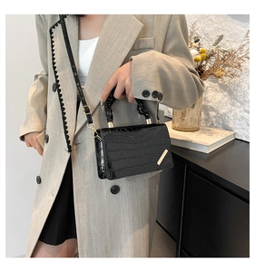 Detail view of black crocodile-embossed leather crossbody bag with pleated handle