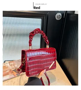 Detail view of red crocodile pattern handbag with pleated handle and golden hardware