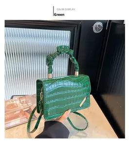 Detailed view of dark green croc-effect handbag with ruched handle and gold buckles