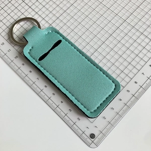 Detailed view of mint green lipstick holder keychain with measurement scale backdrop