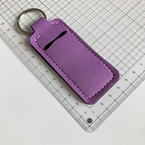 Close-up of a purple neoprene lipstick holder keychain on a white grid measurement board