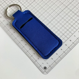 Blue neoprene lipstick holder keychain with metal ring shown next to a scale for sizing
