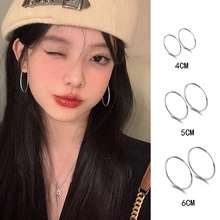 Three sizes of silver geometric hoop earrings shown on model and still life
