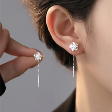 Silver five-petal flower stud earring with long tassel chain on model's ear