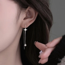 Detail of silver long tassel earrings with sparkling star motifs and cubic zirconia
