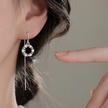Close-up of elegant silver long tassel earrings with sparkling zircon circle charm