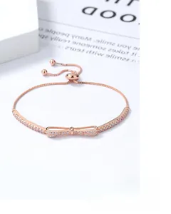 Close-up of rose gold bow bracelet with zircon stones and adjustable pull-chain