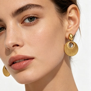 Elegant gold stainless steel earrings with vintage shell texture worn by a model