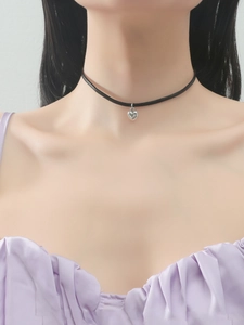 Close-up of a silver heart pendant on a thin black cord choker worn by a model