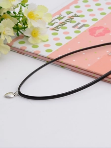 Detailed close-up of a silver heart pendant on a minimalist black cord necklace