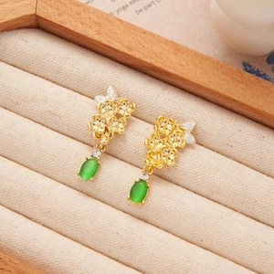 Detail of fan-shaped green bamboo leaf earrings with elegant long tassels and gold finish