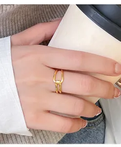 Close-up of golden interlocking double loop ring on a model holding a coffee cup