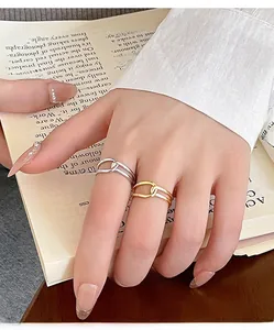 Close-up of minimalist gold and silver knotted rings on fingers with a book background