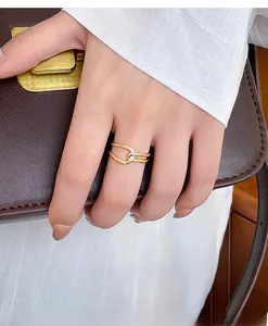 Detailed view of intertwined double gold ring worn on finger against leather background