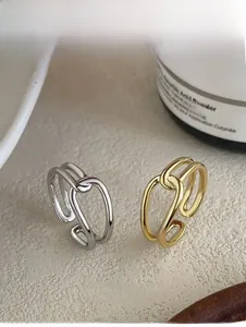 Detail of minimalist knotted double-layer open rings in polished gold and silver finishes