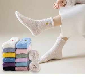 Dettaglio di calze spesse in pile corallo con ricamo a cuore in vari colori pastello