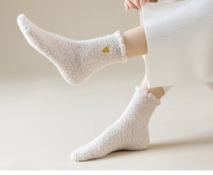 Dettaglio delle calze in pile corallo beige con ricamo a cuore giallo per l'inverno