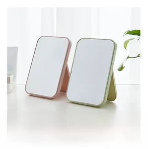 Detail view of pink and green folding vanity mirrors on a desk with a modern minimalist design