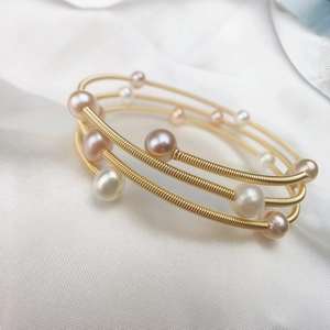 Detailed close-up of handmade 14K gold plated wire wrapped bracelet with freshwater pearls