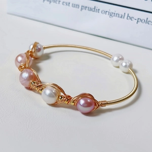 Macro shot of gold wire-wrapped freshwater pearls bracelet with pink and white pearls