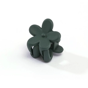 Detail view of small dark green flower hair claw with a matte finish for girls