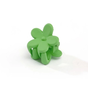 Detail showing a bright green matte flower-shaped hair clip for kids with smooth texture