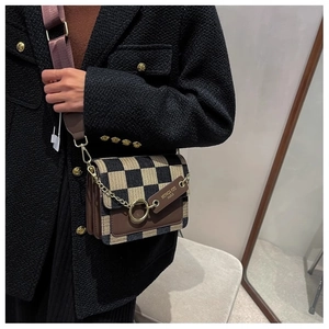 Detail of cross-body bag with yellow-black plaid pattern and leather metal ring buckle