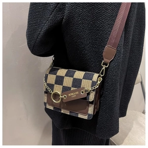 Detail of checkered crossbody bag with metal chain accent and brown leather tag