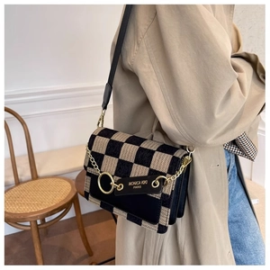 Detail of beige and black checkered crossbody bag featuring gold chain and leather tag