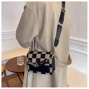 Detail of checkered crossbody bag with gold chain and black leather flap for women