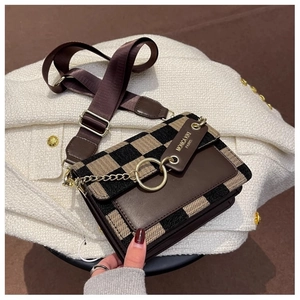 Detail of checkered crossbody bag with gold ring hardware and wide fabric strap