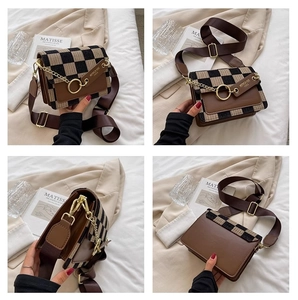 Detail view of the checkered pattern, gold hardware and brown leather trim on a crossbody bag