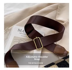 Detail of adjustable dark brown woven nylon shoulder strap with gold hardware buckle