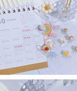 Detail of cute cartoon bear and flower clips organizing a spiral desktop calendar