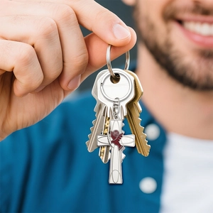 Men holding a creative silver cross keychain with a red peace dove and olive branch