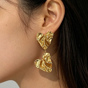 Unregelmäßige Ohrstecker mit zwei Herzen in 18K Goldoptik an einem Model getragen