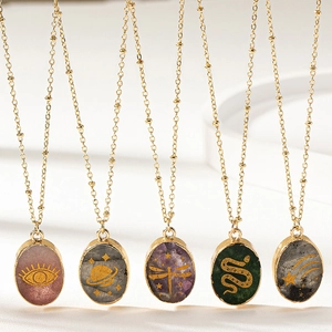 Detail of bohemian gold chains with amethyst and emerald stone pendants with mystic motifs