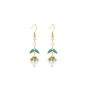 Detail of beaded earrings with green enamel leaves and white pearls in gold finish