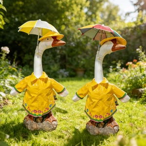 Detail of garden goose statues wearing yellow raincoats and holding miniature umbrellas