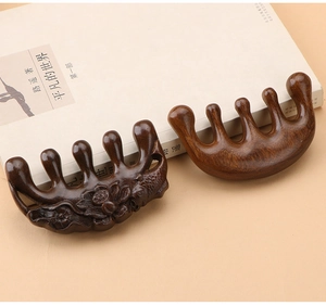 Detail of sandalwood massage combs with lotus carving next to a vintage book
