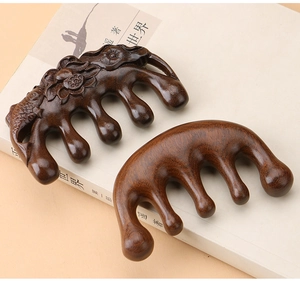 Detail of hand-carved sandalwood massage combs with lotus koi and smooth bead-like teeth