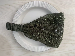 Close-up of dark green floral lace headband decorated with pearls and crystals