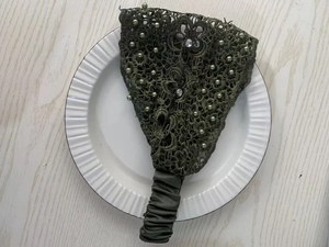 Detail of dark green lace headband with pearls and rhinestones on a white plate