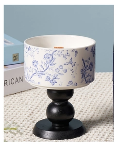 Detailed view of blue floral Toile de Jouy ceramic candle on a black wooden base
