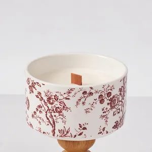 Artistic porcelain scented candle with red floral patterns and a natural wooden base