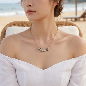 Detailed view of irregular natural green stone pendant on a gold chain necklace